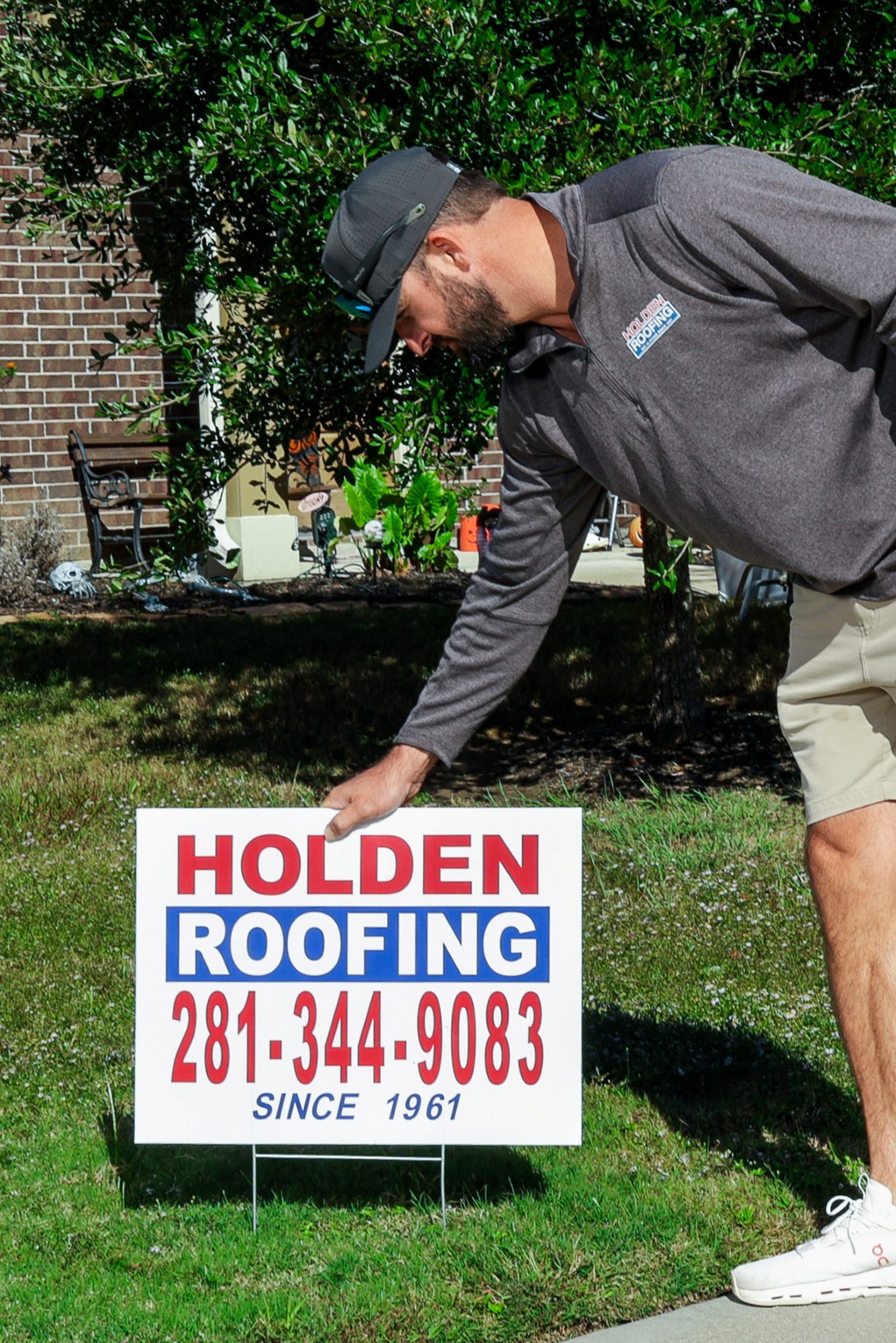 A Holden Roofing yard sign being placed on a lawn