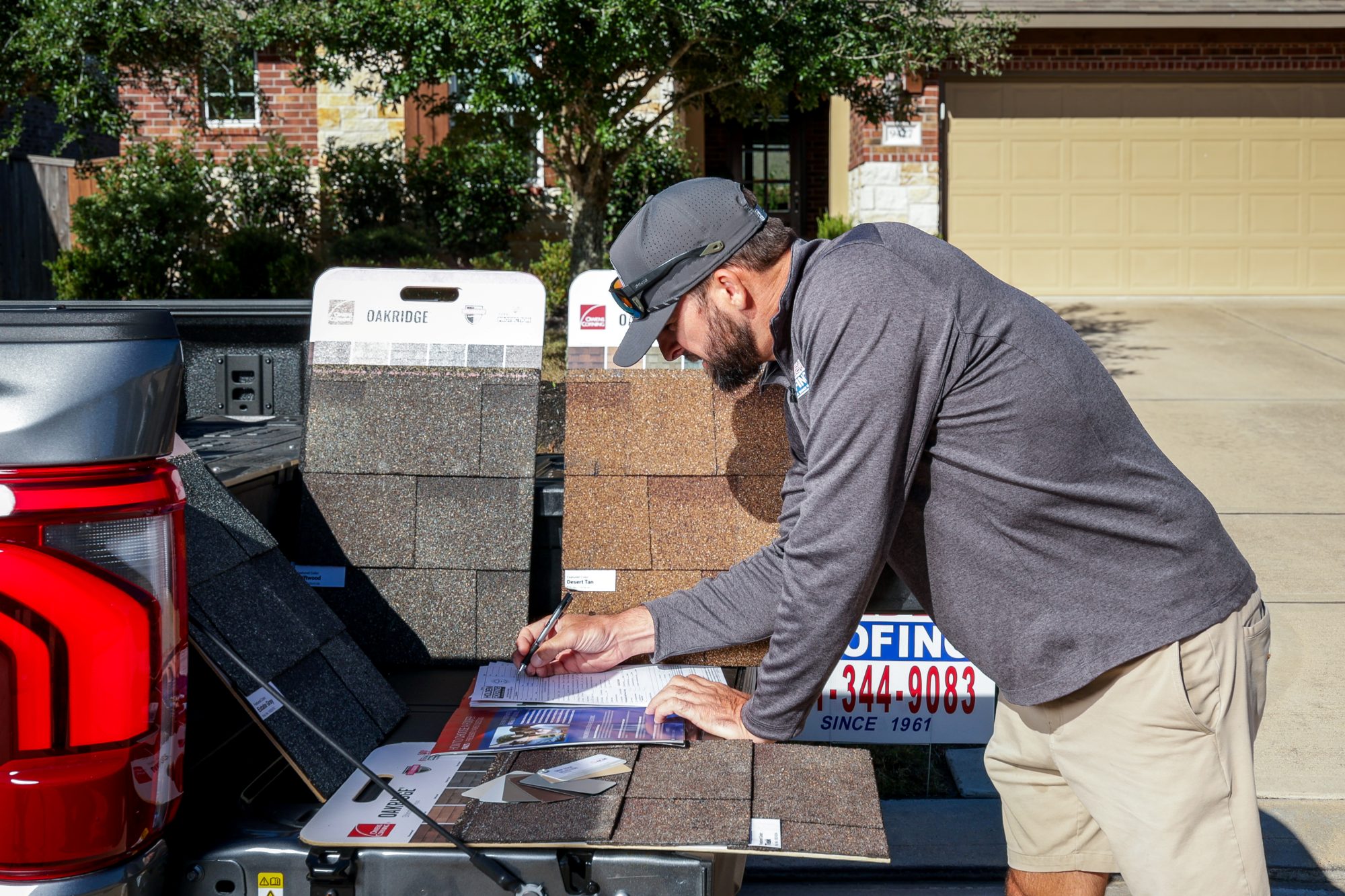 A project manager writing up a scope with shingle samples on the tailgate