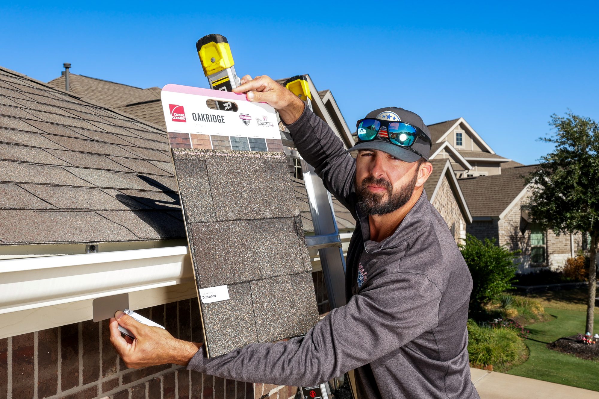 Holding an Owens Corning shingle sample board against the existing roof