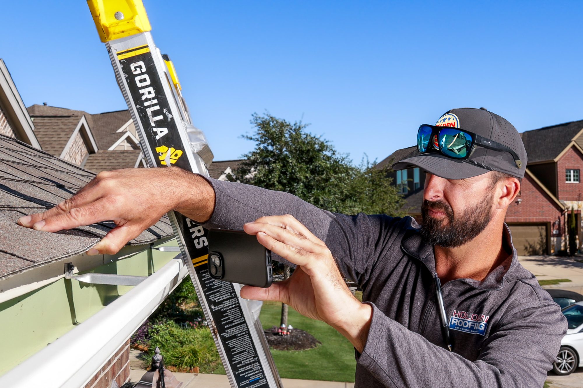 A Holden project manager checking the drip edge and gutter from the ladder