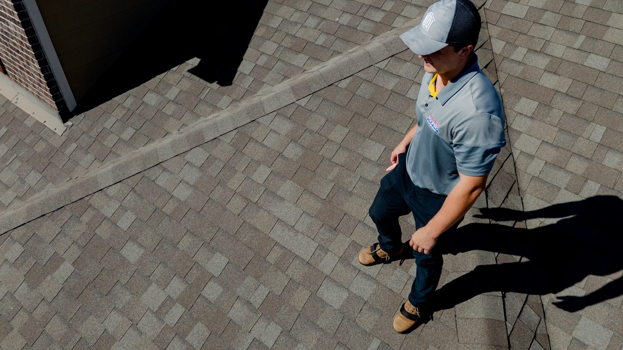 A Holden inspector walking a shingle roof, aerial