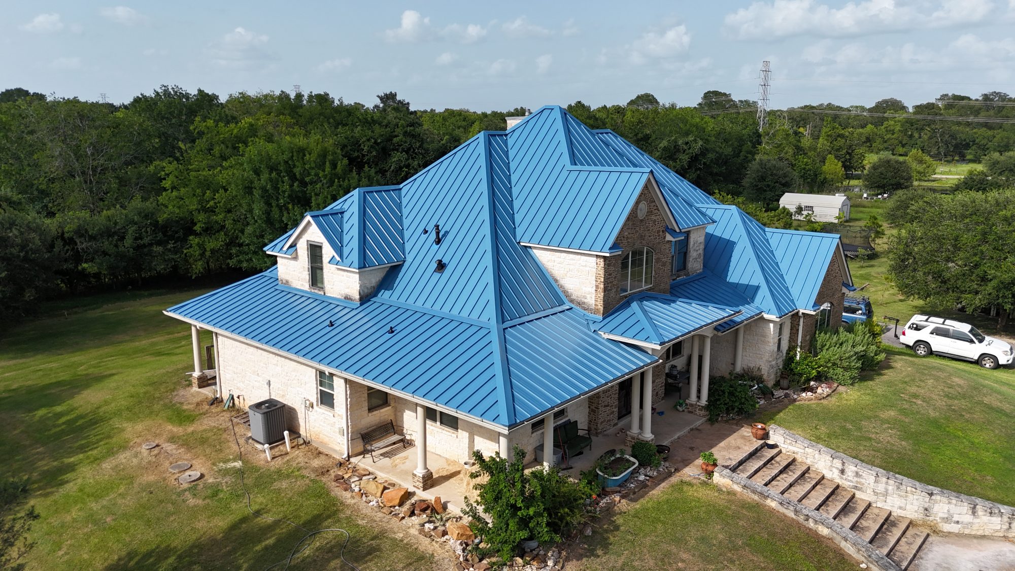 roofing contractor Dripping Springs TX, Holden Roofing Austin crew seaming 24-gauge standing seam metal panels on a ranch-style home in Sawyer Ranch, metal roofing, Class 4 shingle and tile roof replacement serving Dripping Springs, Lakeway, Bee Cave and Buda