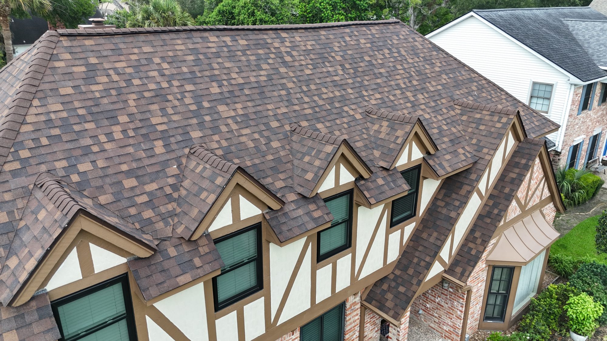Brown architectural shingle roof on a Tudor-style home, aerial