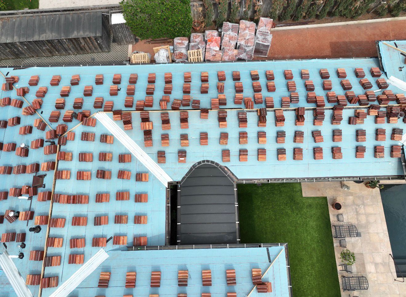 Tile roof mid-install, tiles staged on new underlayment, aerial