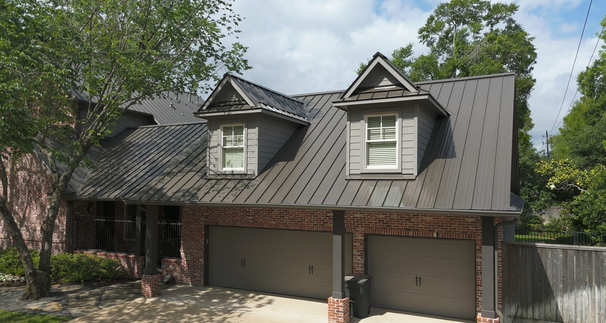 Grey standing seam metal roof with dormers, street view